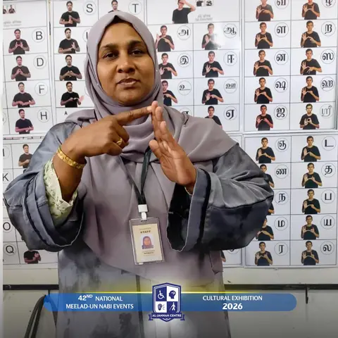 A teacher demonstrating sign language in front of alphabet charts